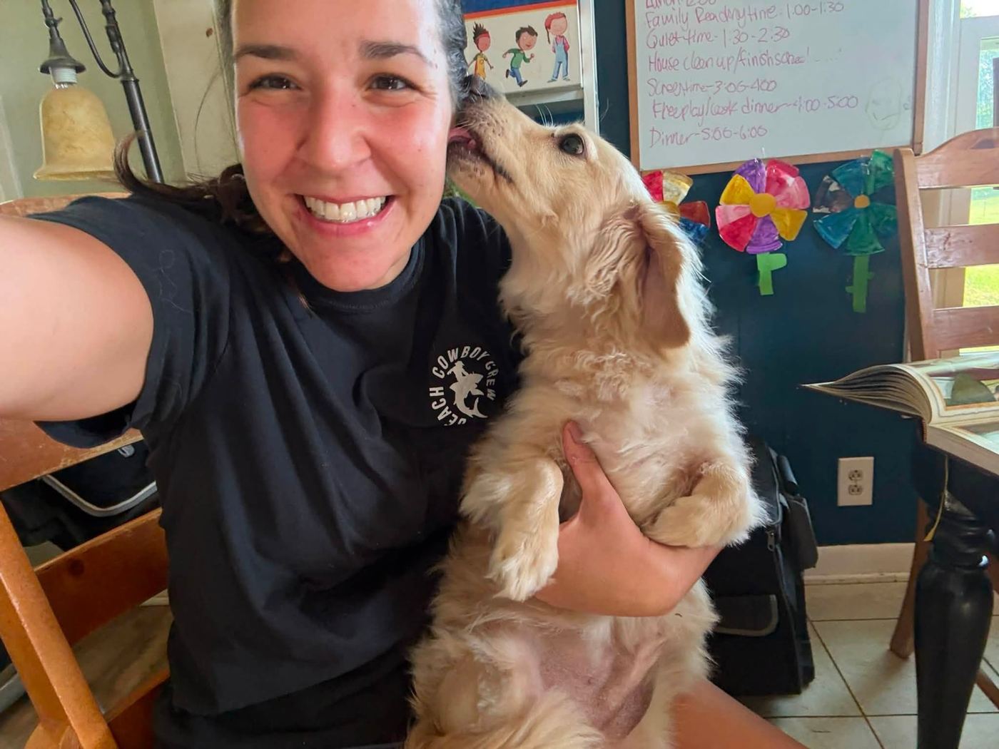 Roslyn getting puppy kisses inside the Devoted Dog Care home